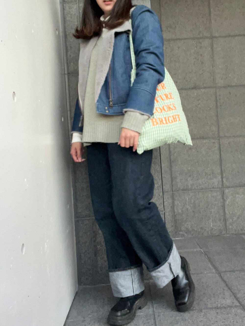 グリーン系のニット/セーター、ブルー系のライダースジャケット、グリーン系のトートバッグを着用したレディースの冬コーディネートの2枚目の写真