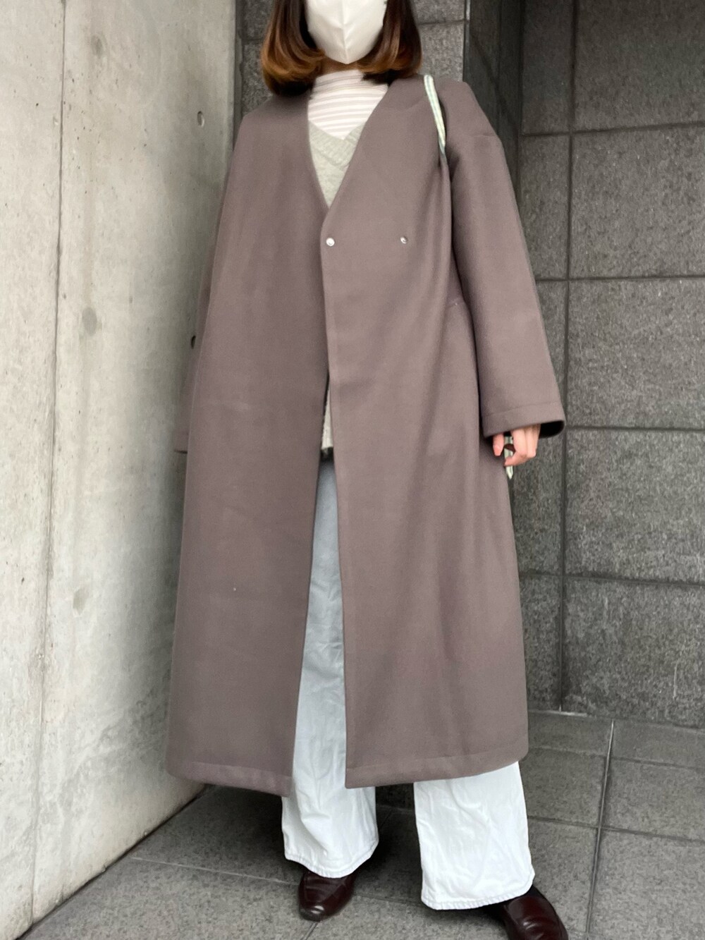 グレー系のノーカラーコート、グリーン系のトートバッグ、ホワイト系のTシャツ/カットソーを着用したレディースの冬コーディネートの2枚目の写真