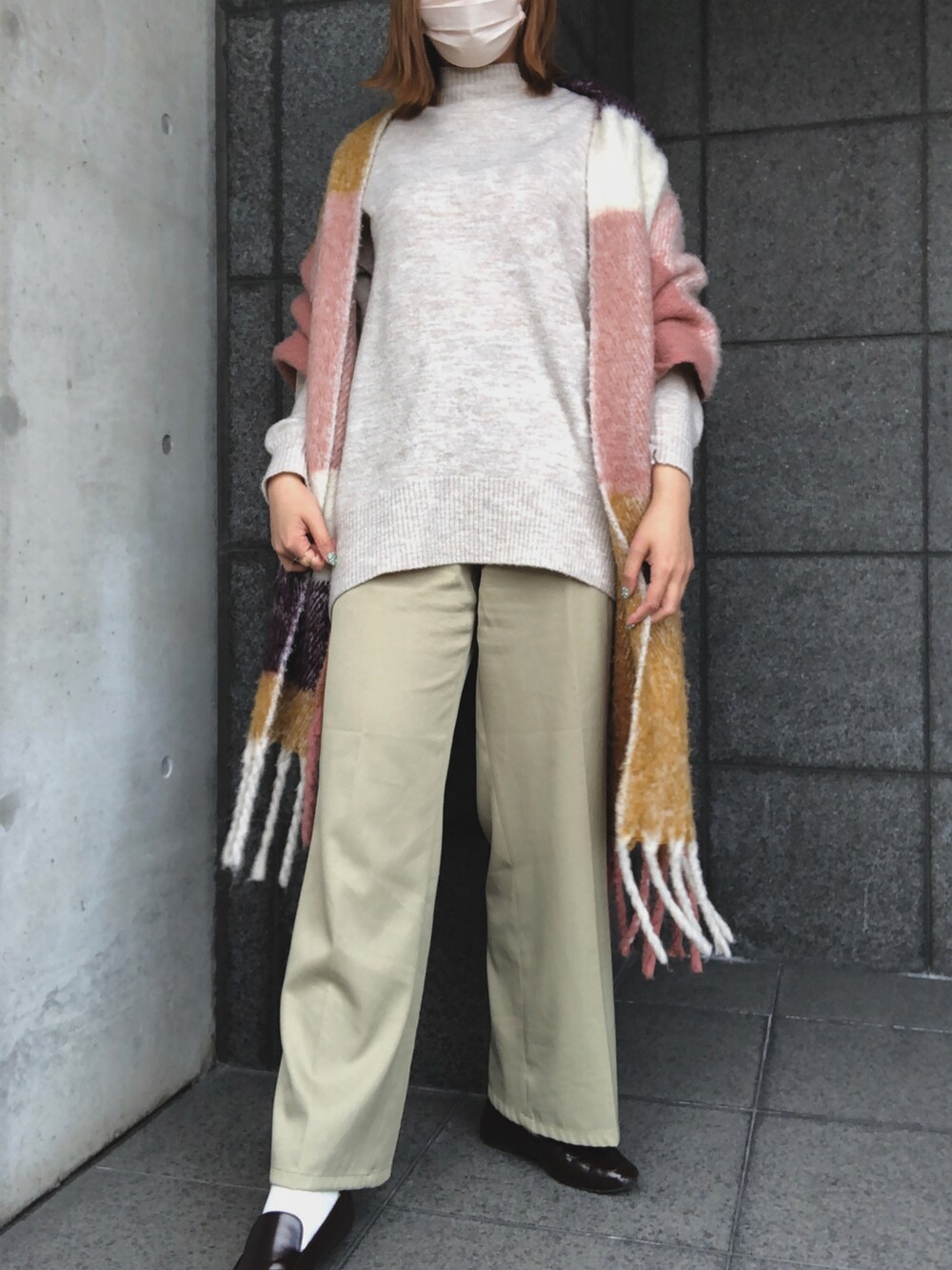 グリーン系のパンツ、ブラウン系のローファー、ベージュ系のニット/セーターを着用したレディースの冬コーディネートの2枚目の写真