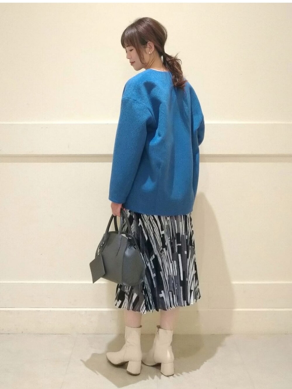 ホワイト系のニット/セーター、ブルー系のノーカラーコート、グレー系のショルダーバッグを着用したレディースの冬コーディネートの2枚目の写真