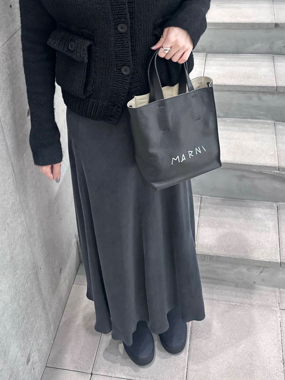 ブルー系のブーツ、ブラック系のニット/セーター、グレー系のスカートを着用したレディースの冬コーディネートの3枚目の写真