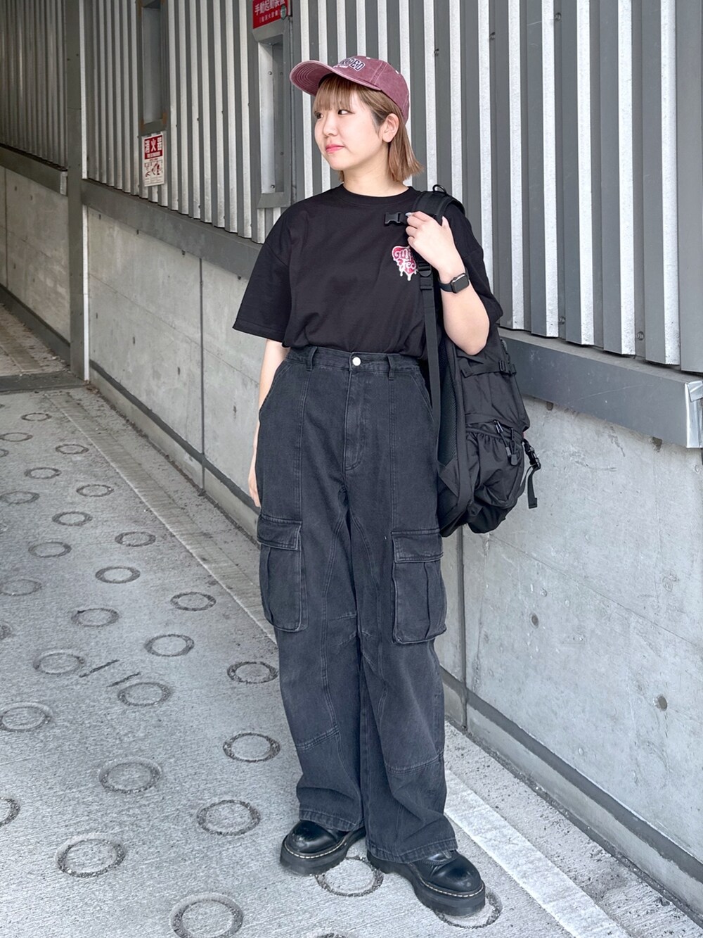 ブラック系のTシャツ/カットソー、ブラック系のカーゴパンツ、レッド系のキャップを着用したレディースの春コーディネートの2枚目の写真