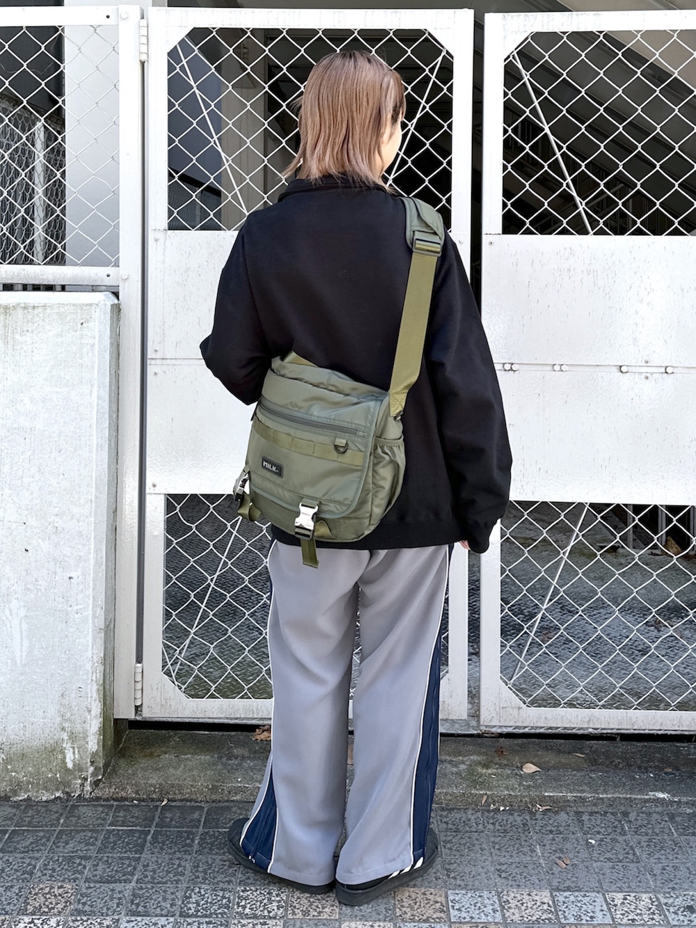 ブラック系のスウェット、グレー系のその他パンツ、グリーン系のメッセンジャーバッグを着用したレディースの春コーディネートの2枚目の写真
