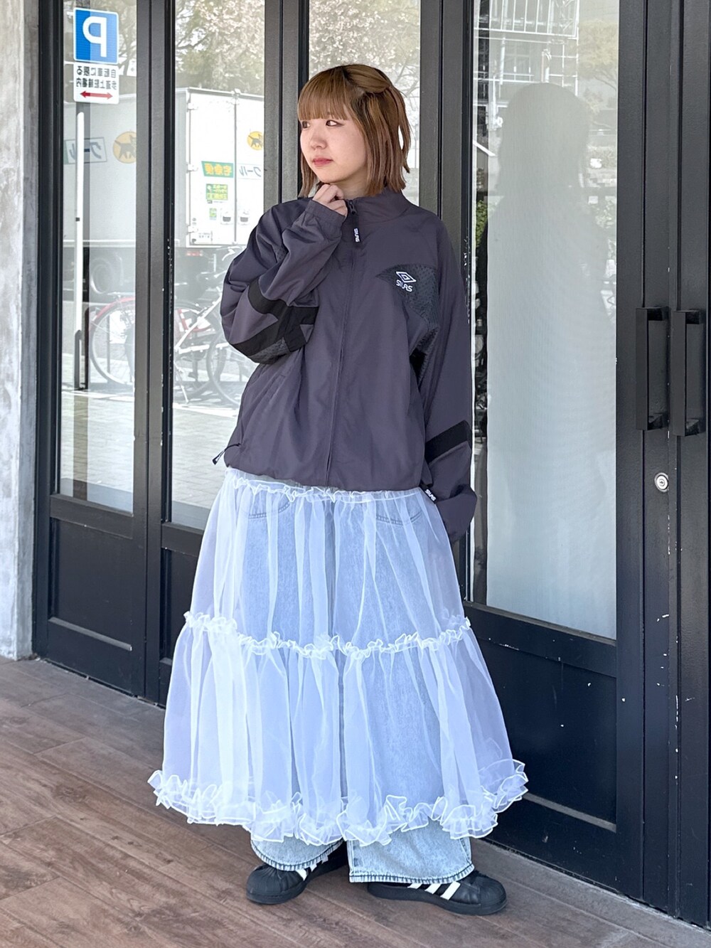 ブルー系のデニムパンツ、ホワイト系のスカート、ブラック系のメッセンジャーバッグを着用したレディースの春コーディネートの3枚目の写真