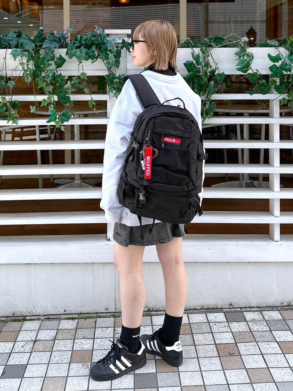 ブラック系のシャツ/ブラウス、レッド系のバックパック/リュック、グレー系のカーディガン/ボレロを着用したレディースの冬コーディネートの2枚目の写真