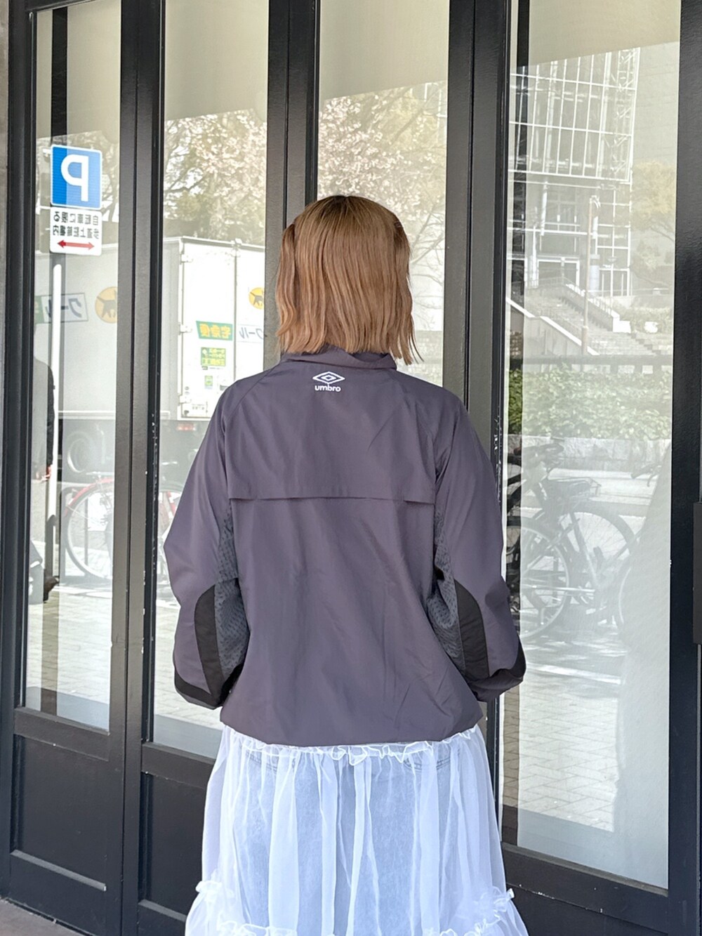 ブルー系のデニムパンツ、ホワイト系のスカート、ブラック系のメッセンジャーバッグを着用したレディースの春コーディネートの7枚目の写真