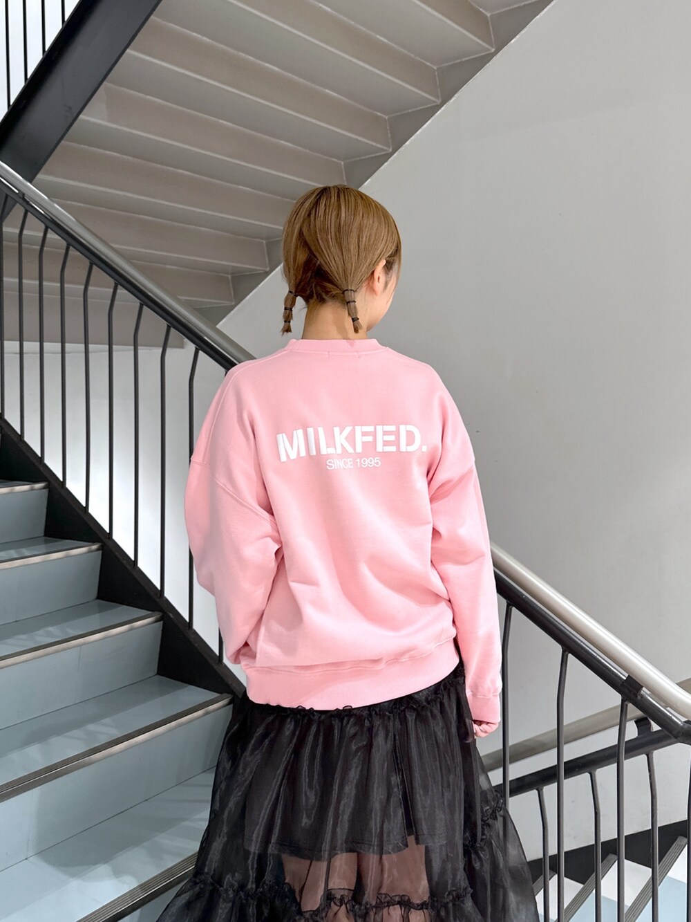 ピンク系のスウェット、ブラック系のスカート、ブラック系のデニムスカートを着用したレディースの春コーディネートの6枚目の写真