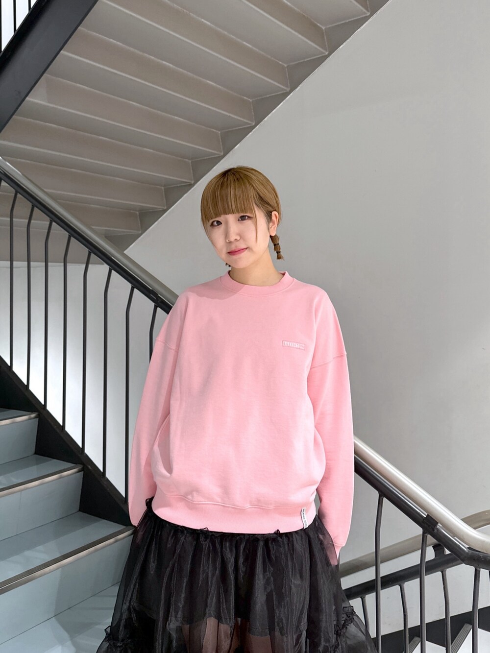 ピンク系のスウェット、ブラック系のスカート、ブラック系のデニムスカートを着用したレディースの春コーディネートの5枚目の写真