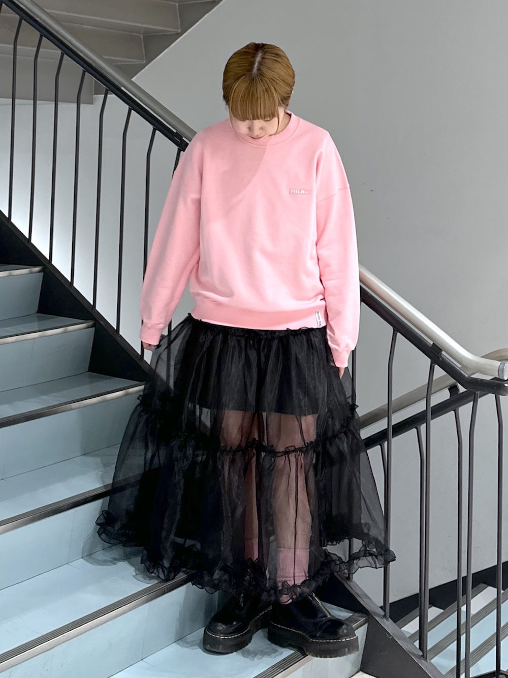 ピンク系のスウェット、ブラック系のスカート、ブラック系のデニムスカートを着用したレディースの春コーディネートの3枚目の写真