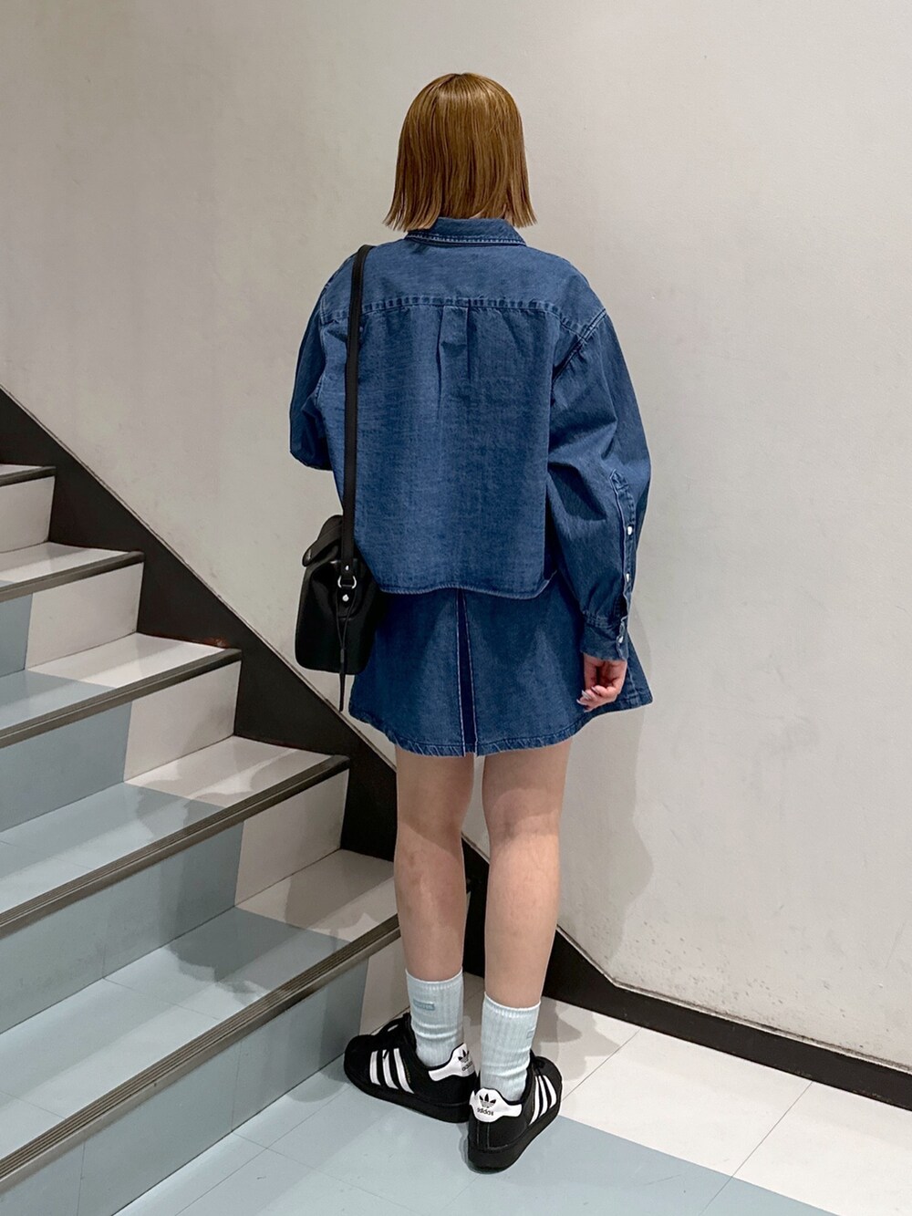 ブルー系のシャツ/ブラウス、ブラック系のショルダーバッグ、ホワイト系のTシャツ/カットソーを着用したレディースの春コーディネートの3枚目の写真
