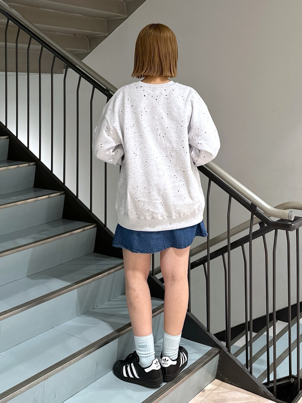 グレー系のスウェット、レッド系のバックパック/リュック、ブルー系のデニムスカートを着用したレディースの春コーディネートの4枚目の写真