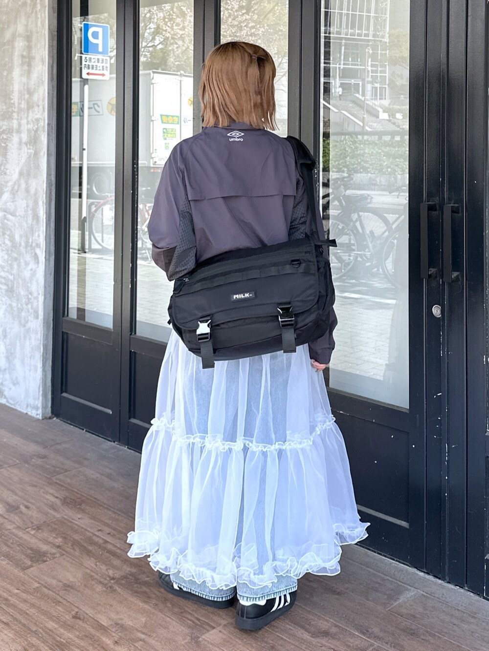 ブルー系のデニムパンツ、ホワイト系のスカート、ブラック系のメッセンジャーバッグを着用したレディースの春コーディネートの2枚目の写真