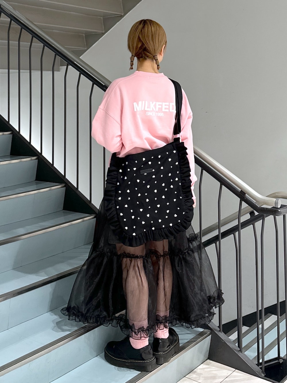 ピンク系のスウェット、ブラック系のスカート、ブラック系のデニムスカートを着用したレディースの春コーディネートの2枚目の写真