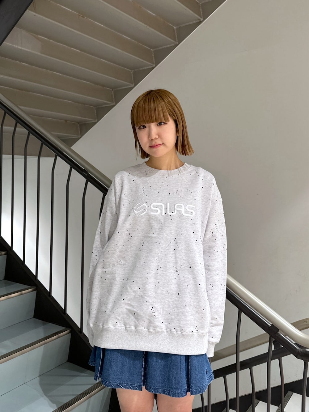 グレー系のスウェット、レッド系のバックパック/リュック、ブルー系のデニムスカートを着用したレディースの春コーディネートの5枚目の写真