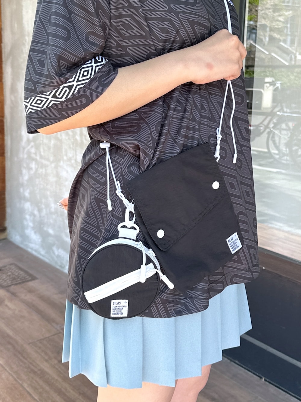 「ショルダーバッグ、休日スタイル、スポーツミックス、おでかけコーデ、ストリート、デートコーデ、メンズライク、プリーツスカート、スカート、お洒落さんとつながりたい、ootd、春夏コーデ、夏コーデ、夏だ！Tシャツ着よう！」｜「SILASのSILAS × UMBRO GAME SHIRT（シャツ/ブラウス、ブラック系）」を使った、ゆんさん（レディース・159cm）の春コーディネートの7枚目の写真