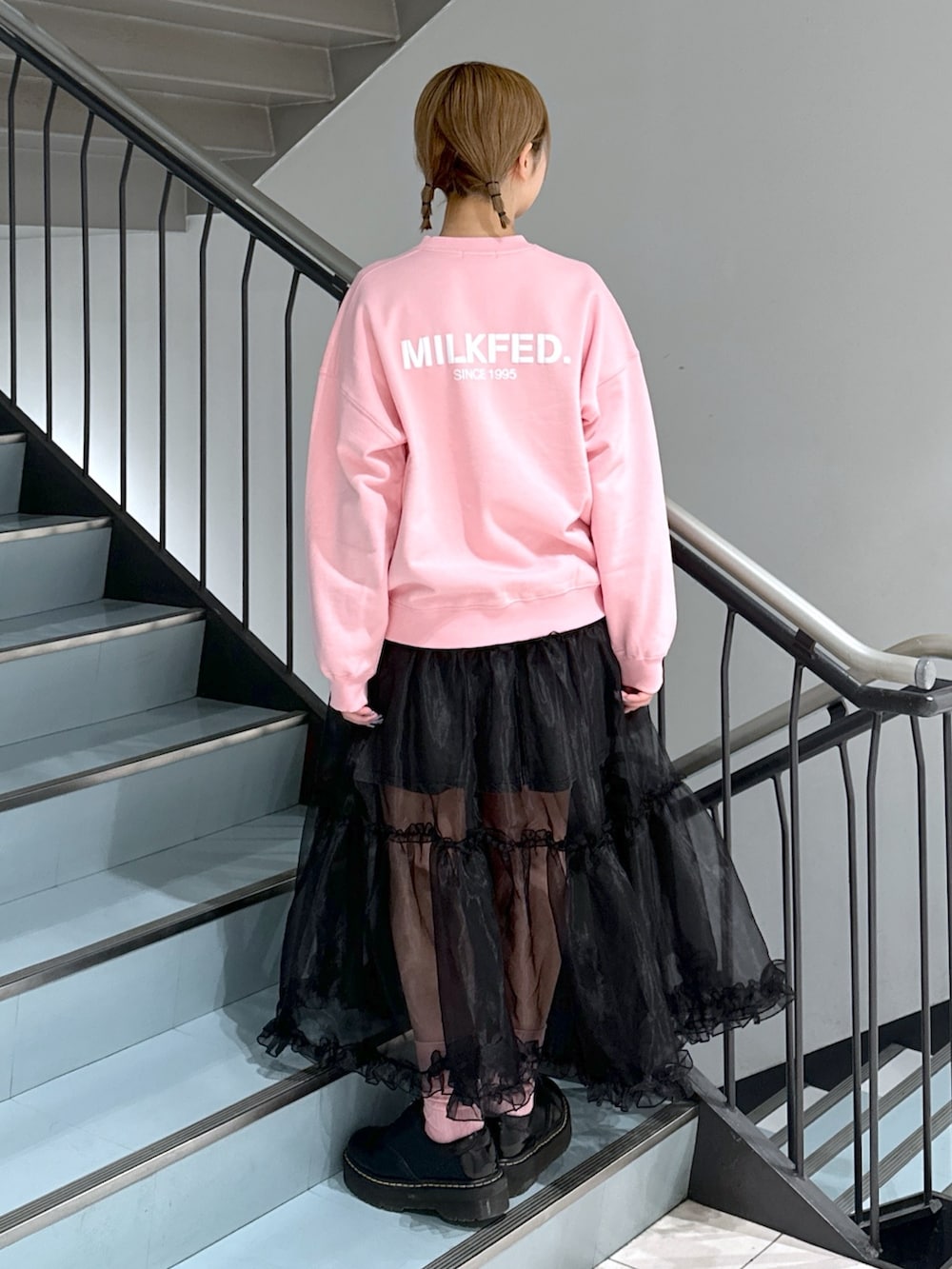 ピンク系のスウェット、ブラック系のスカート、ブラック系のデニムスカートを着用したレディースの春コーディネートの4枚目の写真