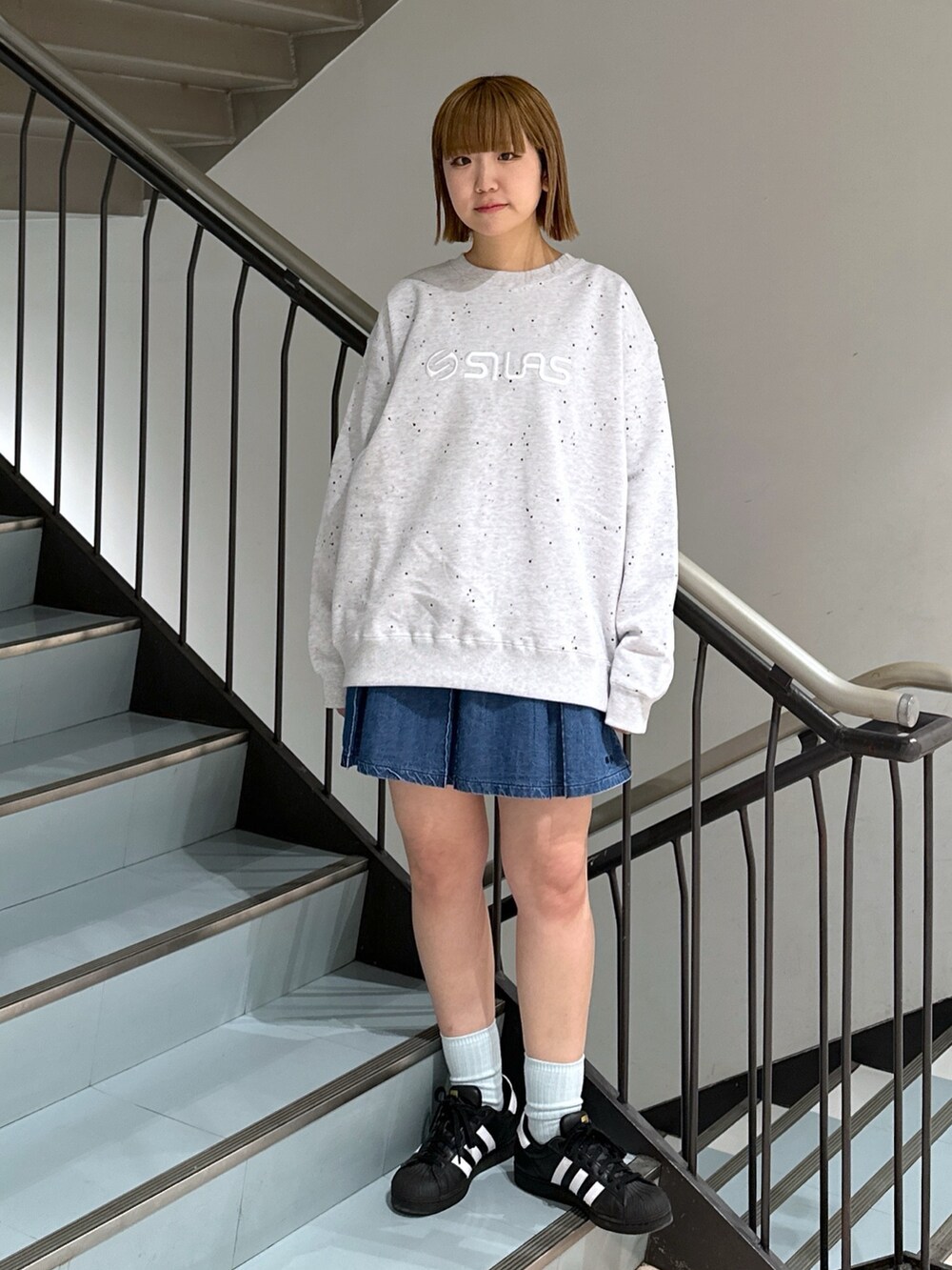 グレー系のスウェット、レッド系のバックパック/リュック、ブルー系のデニムスカートを着用したレディースの春コーディネートの3枚目の写真