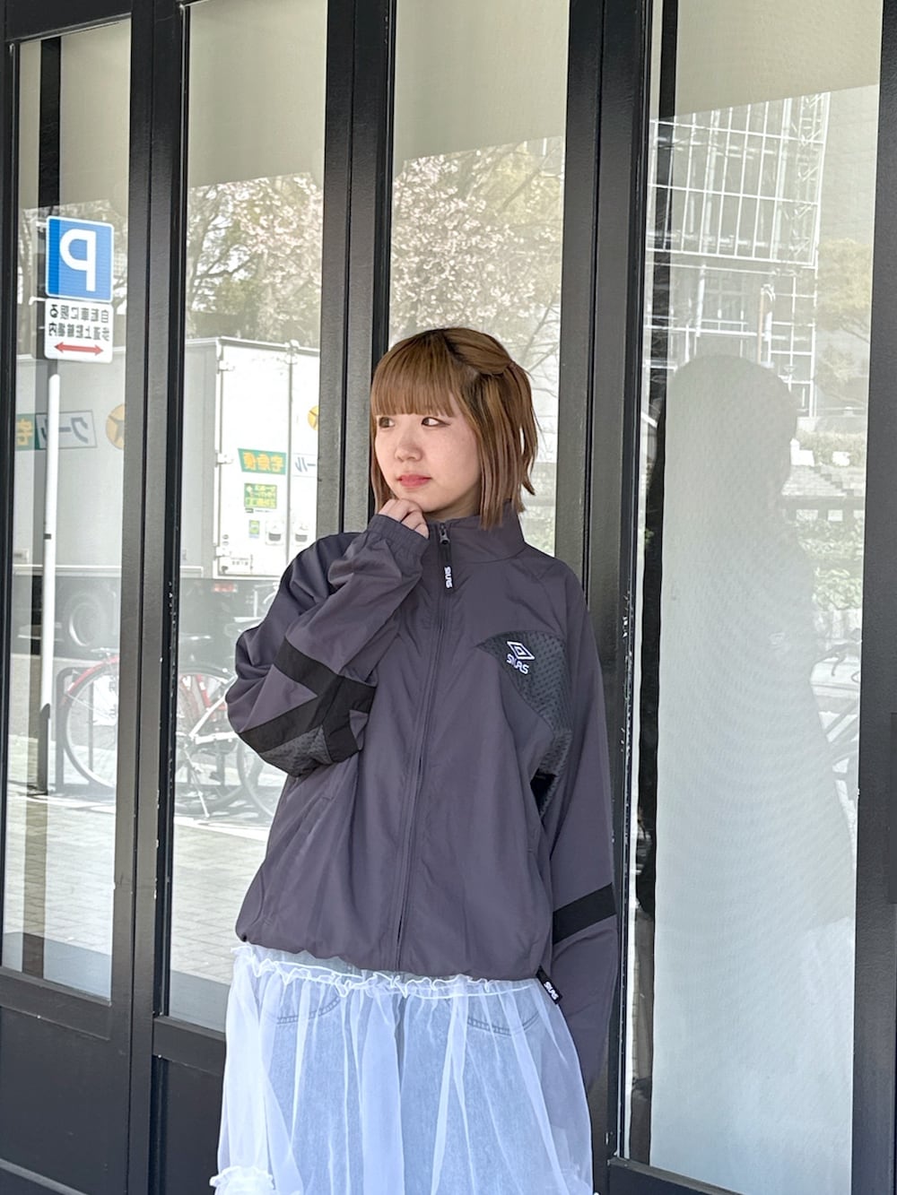 ブルー系のデニムパンツ、ホワイト系のスカート、ブラック系のメッセンジャーバッグを着用したレディースの春コーディネートの6枚目の写真