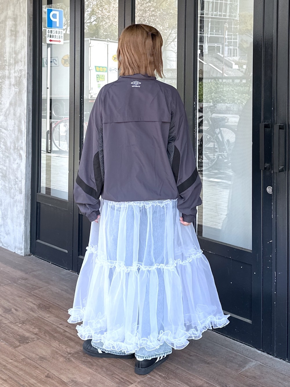 ブルー系のデニムパンツ、ホワイト系のスカート、ブラック系のメッセンジャーバッグを着用したレディースの春コーディネートの5枚目の写真