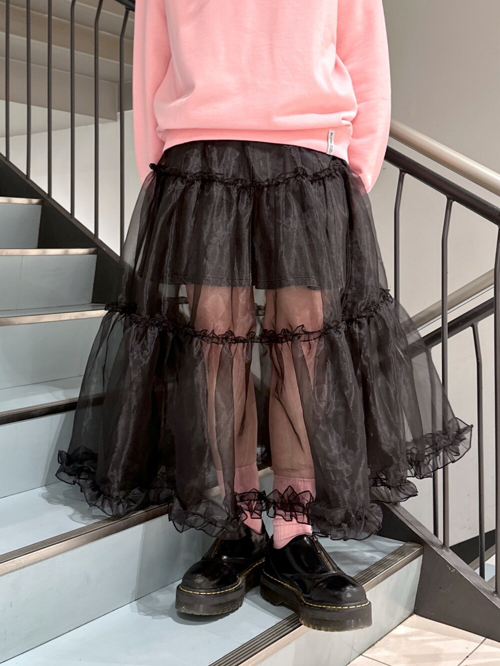 ピンク系のスウェット、ブラック系のスカート、ブラック系のデニムスカートを着用したレディースの春コーディネートの7枚目の写真