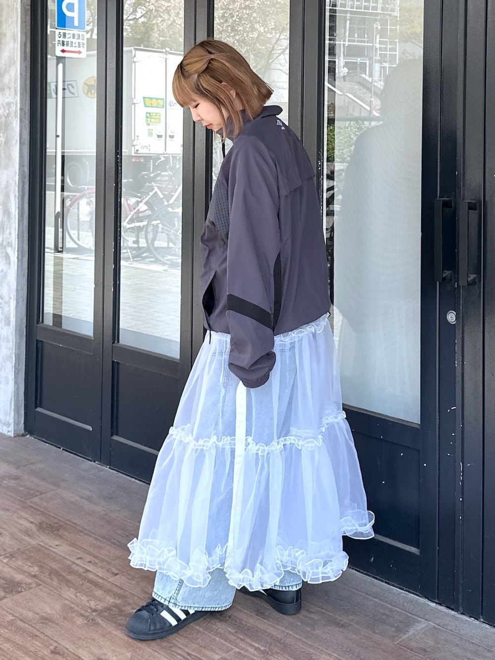 ブルー系のデニムパンツ、ホワイト系のスカート、ブラック系のメッセンジャーバッグを着用したレディースの春コーディネートの4枚目の写真