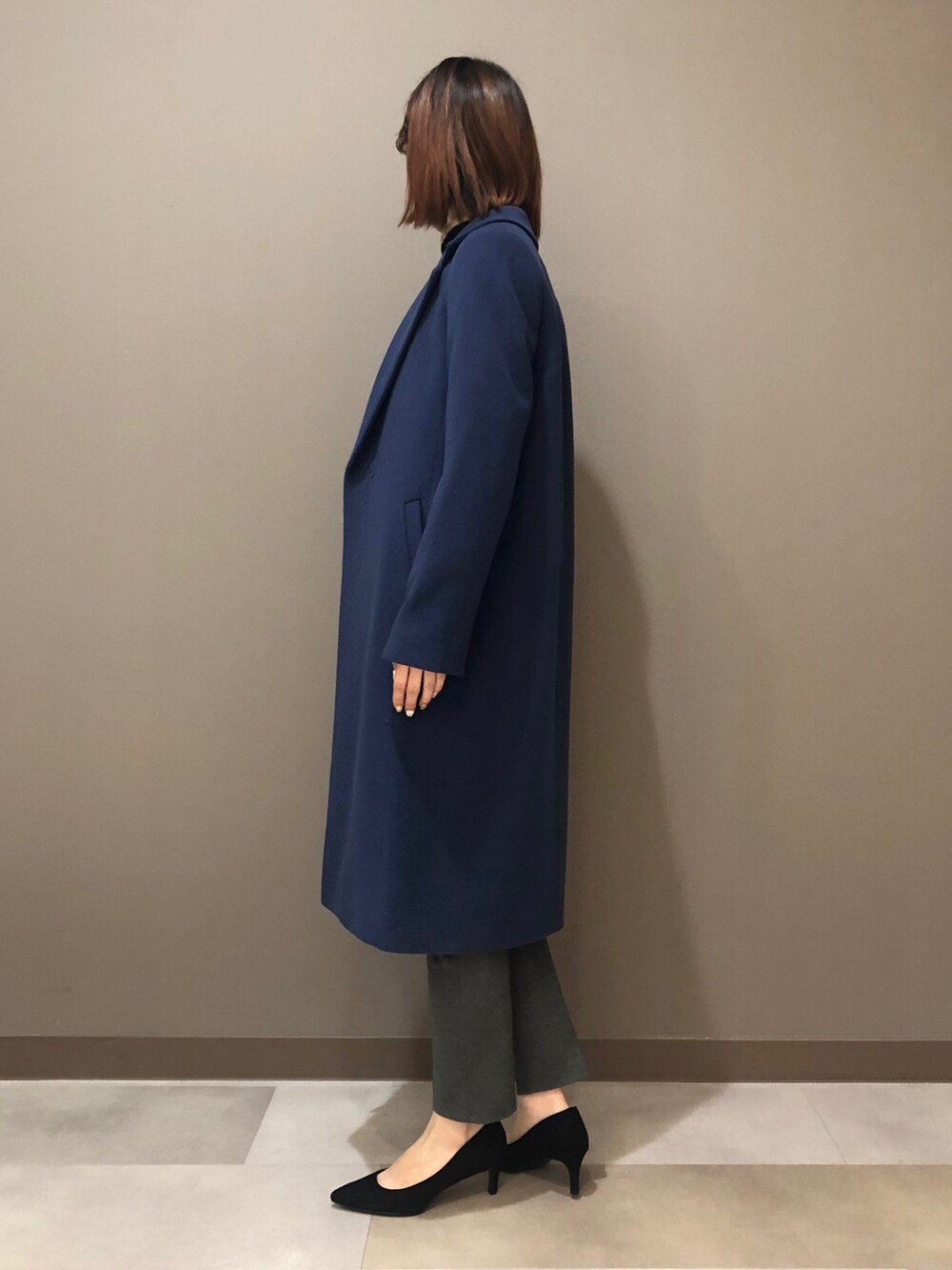 ベージュ系のニット/セーター、ブルー系のチェスターコート、グレー系のスーツパンツを着用したレディースの冬コーディネートの3枚目の写真