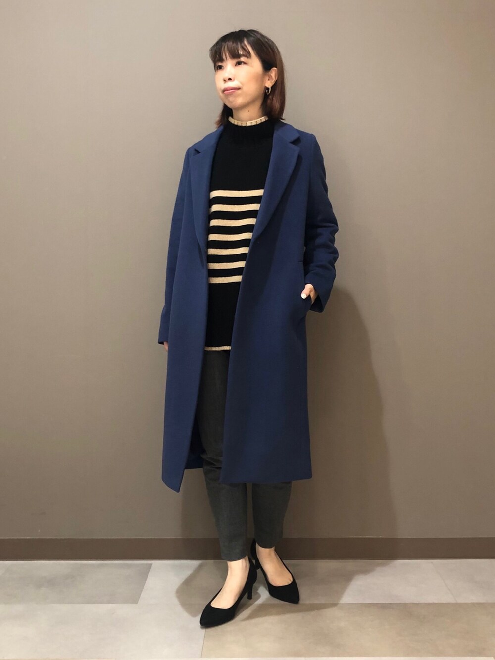 ベージュ系のニット/セーター、ブルー系のチェスターコート、グレー系のスーツパンツを着用したレディースの冬コーディネートの2枚目の写真