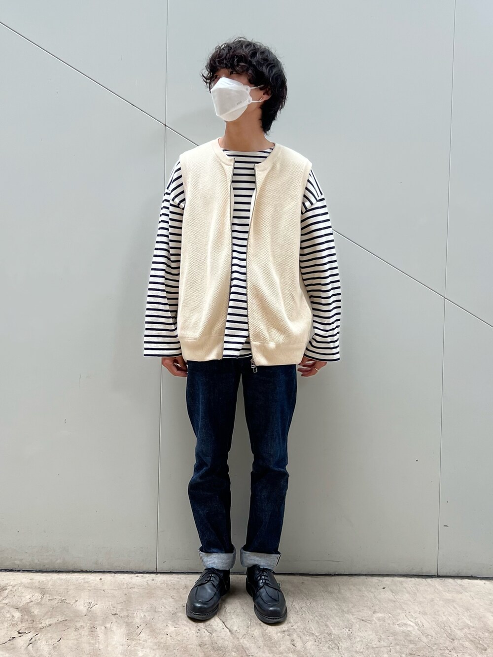 ブルー系のデニムパンツ、ベージュ系のベスト、ホワイト系のTシャツ/カットソーを着用したメンズの春コーディネートの4枚目の写真