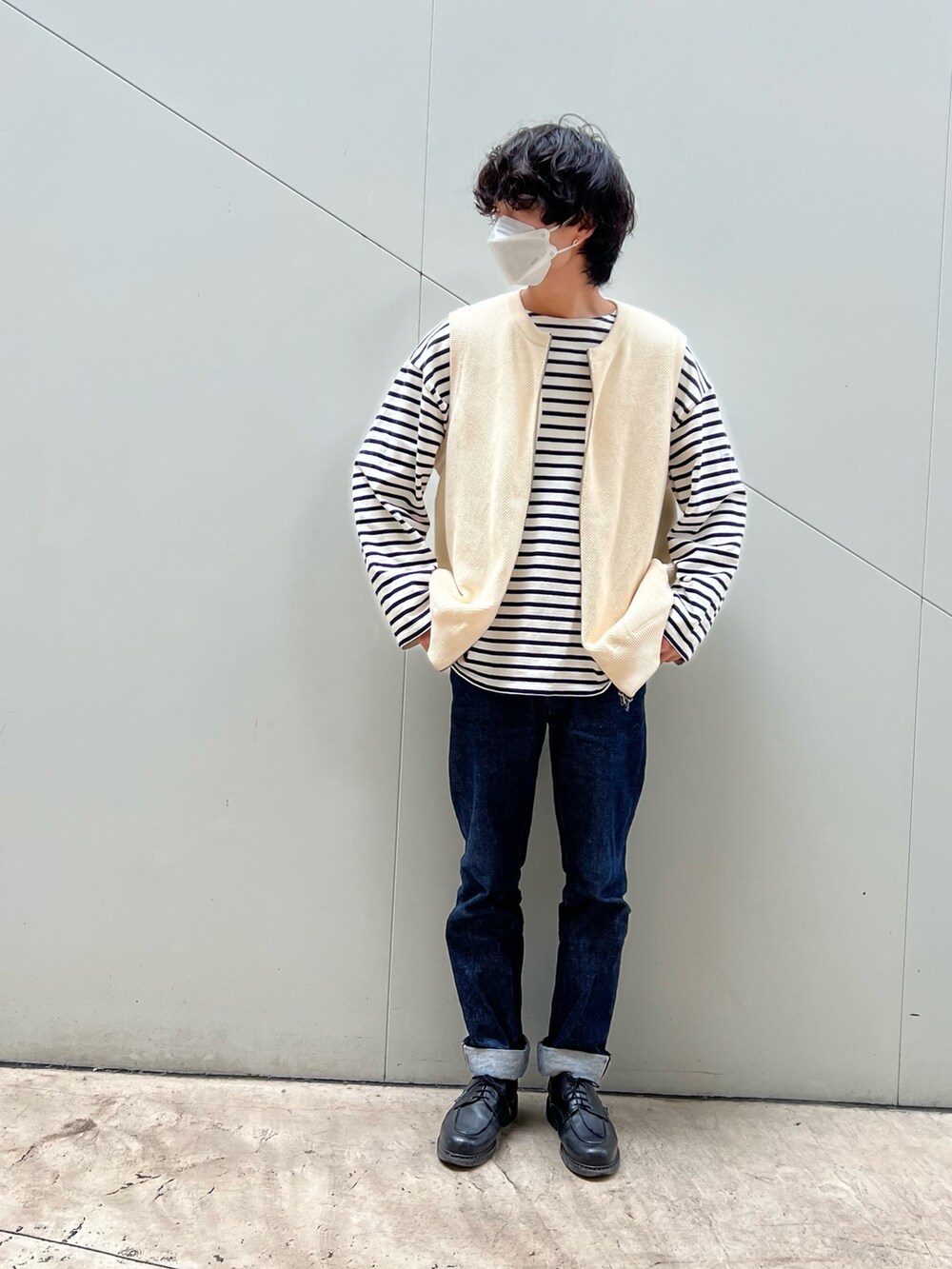 ブルー系のデニムパンツ、ベージュ系のベスト、ホワイト系のTシャツ/カットソーを着用したメンズの春コーディネートの2枚目の写真