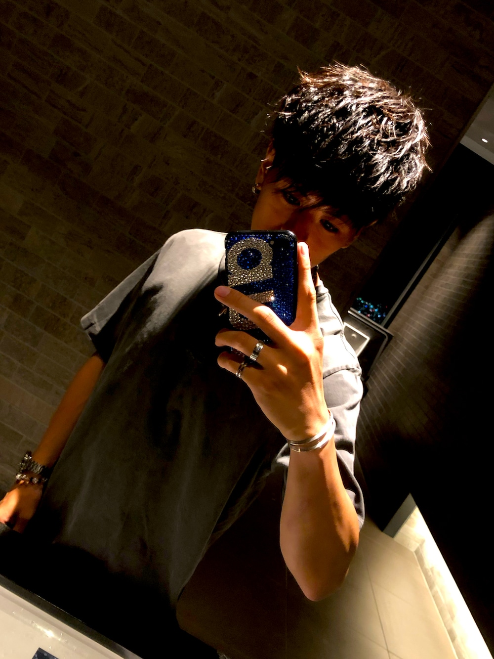 グレー系のTシャツ/カットソー、レッド系のクラッチバッグ、ブラック系のデニムパンツを着用したメンズの冬コーディネートの2枚目の写真