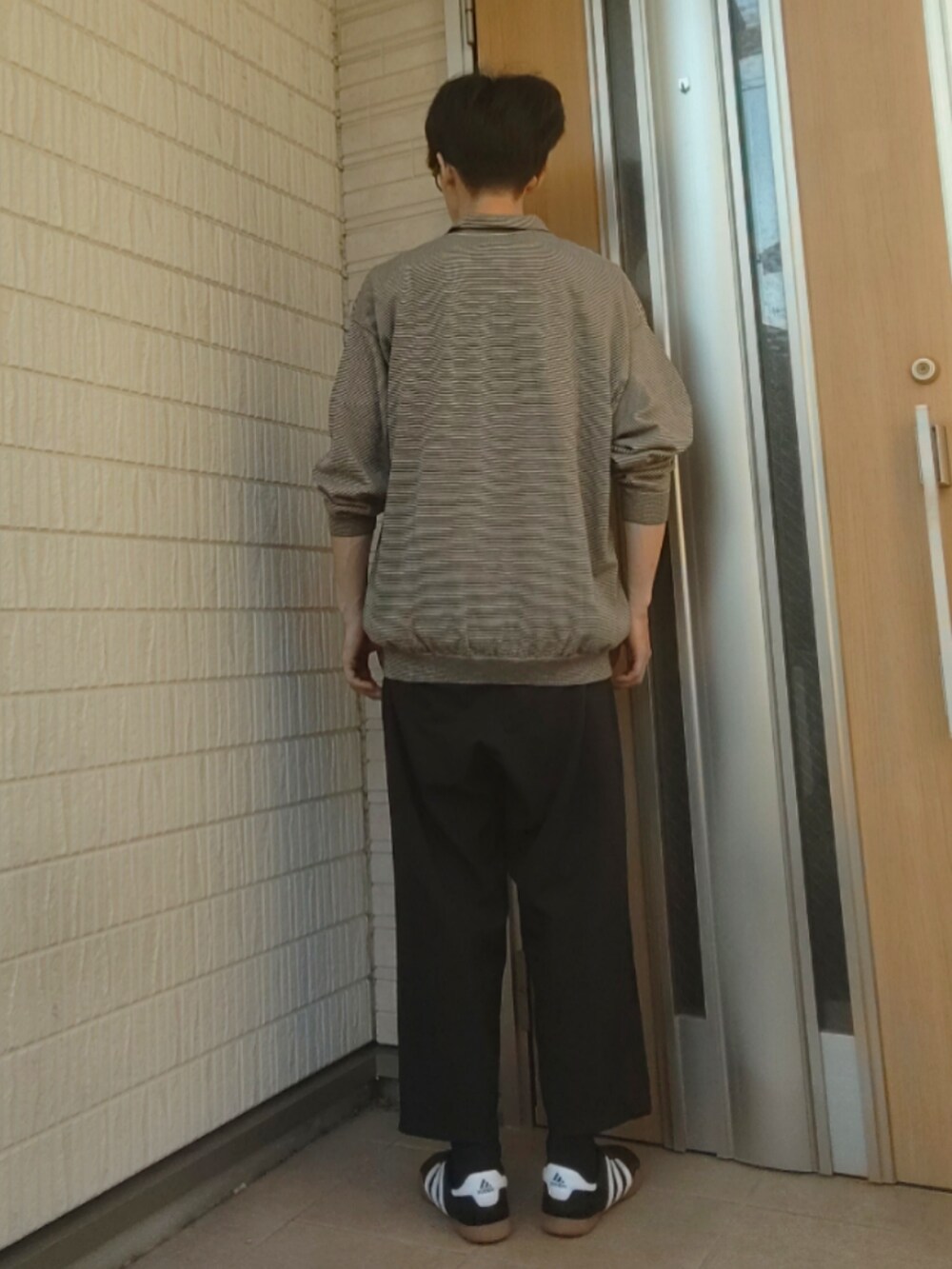 グレー系のポロシャツ、ブラック系のパンツ、ブラック系のスニーカーを着用したメンズの夏コーディネートの3枚目の写真