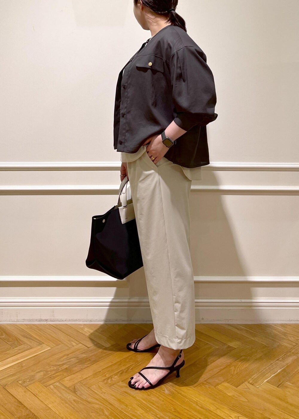ブラック系のハンドバッグ、ベージュ系のシャツ/ブラウス、ブラック系のサンダルを着用したレディースの夏コーディネートの4枚目の写真