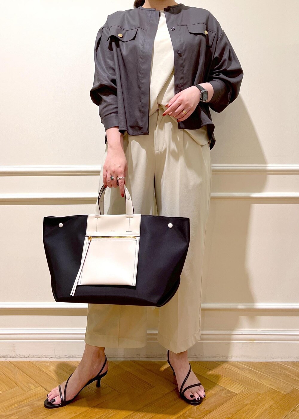 ブラック系のハンドバッグ、ベージュ系のシャツ/ブラウス、ブラック系のサンダルを着用したレディースの夏コーディネートの3枚目の写真