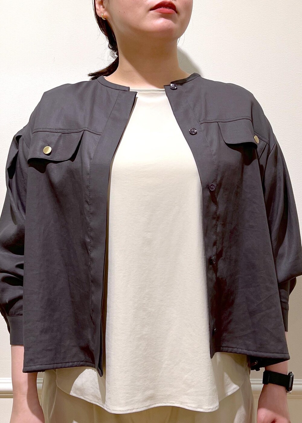 ブラック系のハンドバッグ、ベージュ系のシャツ/ブラウス、ブラック系のサンダルを着用したレディースの夏コーディネートの2枚目の写真