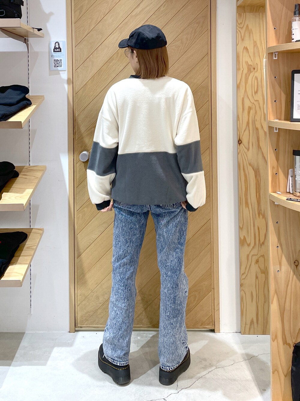 ホワイト系のスウェット、ブルー系のデニムパンツ、ブラック系のキャップを着用したレディースの冬コーディネートの2枚目の写真