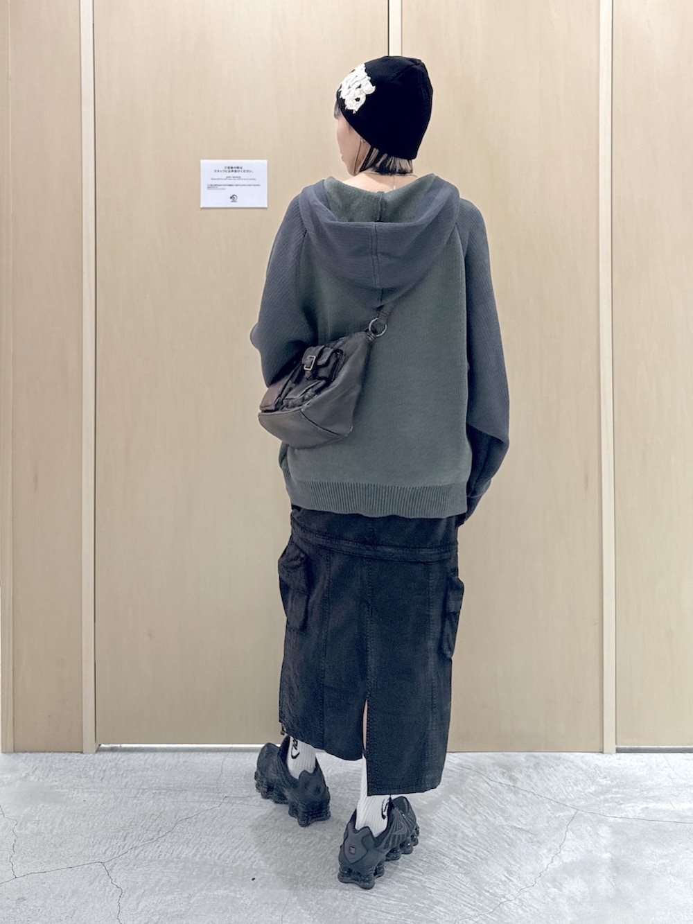 ブラック系のショルダーバッグ、ブラック系のスカート、グリーン系のニット/セーターを着用したレディースの冬コーディネートの3枚目の写真