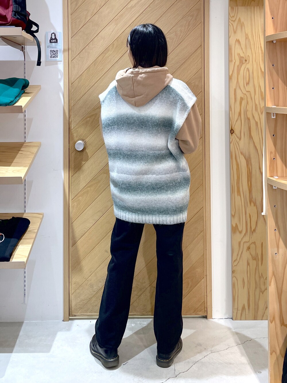 グレー系のベスト、ベージュ系のパーカー、ブラック系のデニムパンツを着用したレディースの秋コーディネートの2枚目の写真