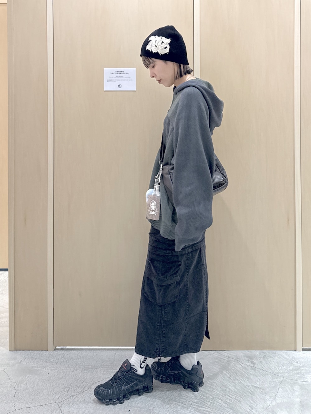 ブラック系のショルダーバッグ、ブラック系のスカート、グリーン系のニット/セーターを着用したレディースの冬コーディネートの2枚目の写真