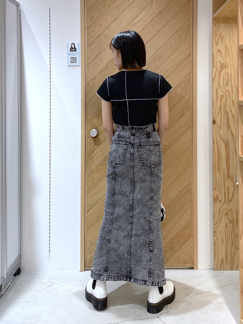 ブラック系のTシャツ/カットソー、ブラック系のデニムスカート、ホワイト系のハンドバッグを着用したレディースの夏コーディネートの2枚目の写真