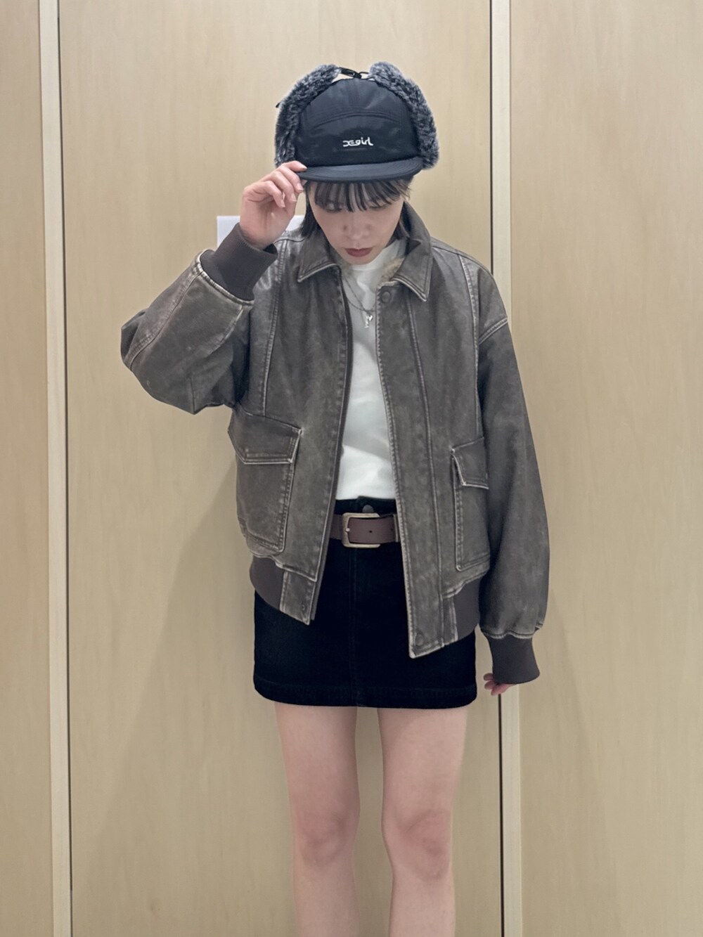 ブラウン系のブルゾン、ホワイト系のTシャツ/カットソー、ブラック系のデニムスカートを着用したレディースの秋コーディネートの4枚目の写真