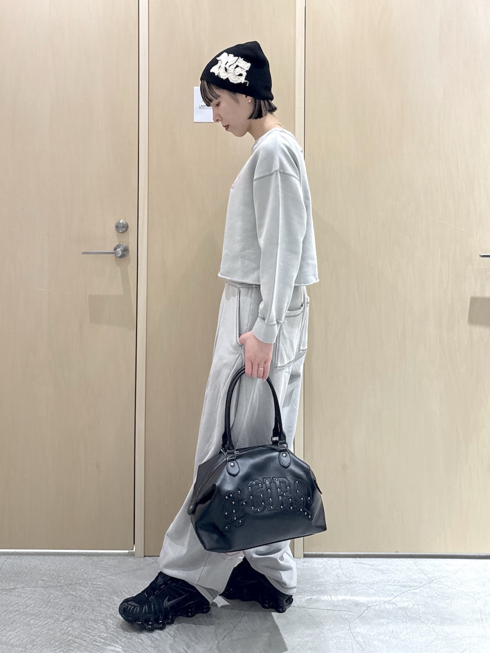 グレー系のスウェット、ブラック系のショルダーバッグ、グレー系のスウェットパンツを着用したレディースの春コーディネートの2枚目の写真