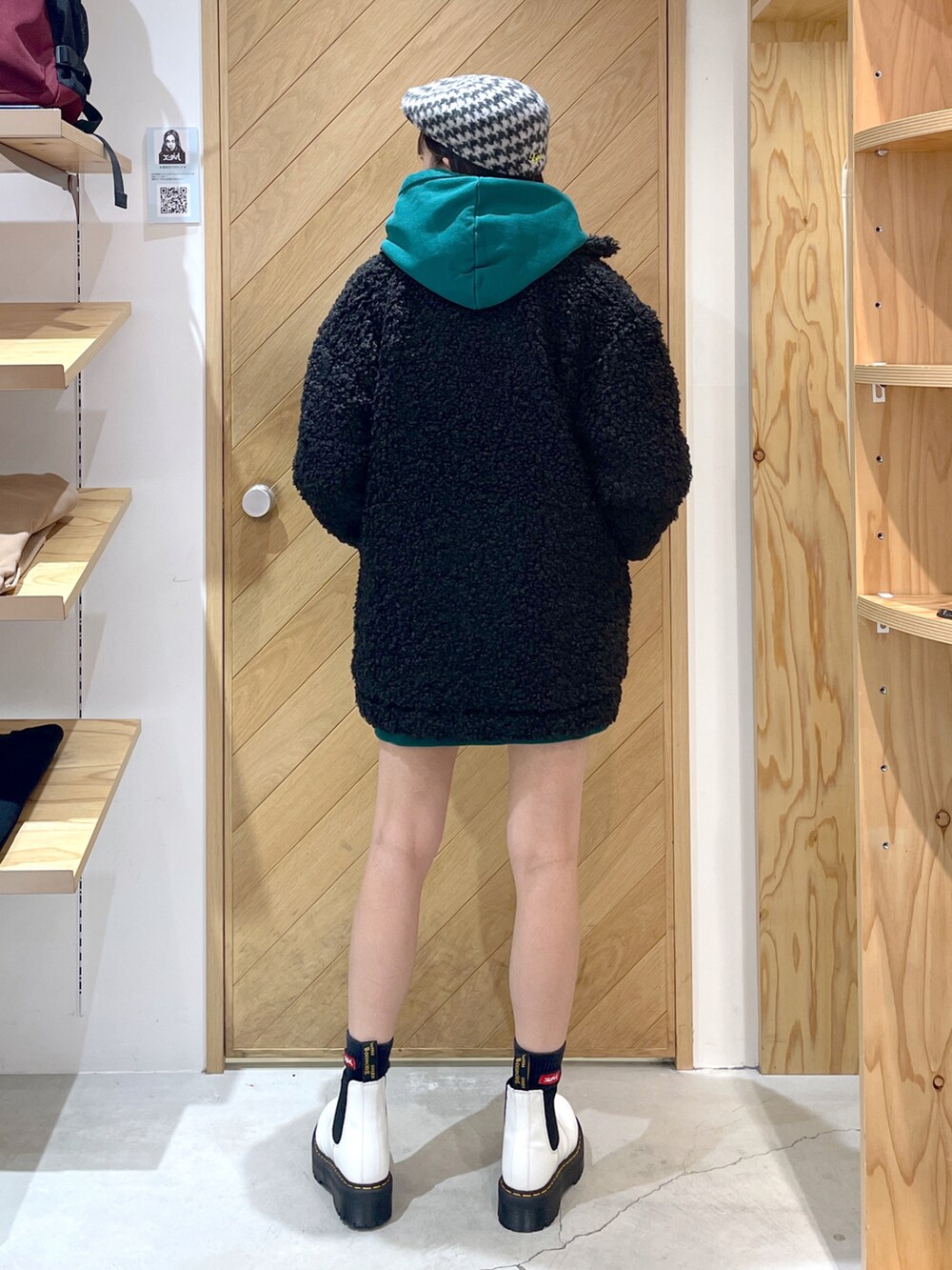 グリーン系のパーカー、ブラック系のその他アウター、ホワイト系のハンチング/ベレー帽を着用したレディースの秋コーディネートの2枚目の写真