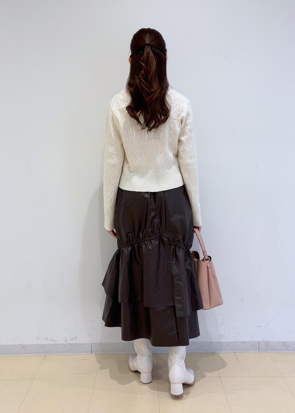 ピンク系のショルダーバッグ、ホワイト系のブーツ、ブラウン系のスカートを着用したレディースの冬コーディネートの4枚目の写真