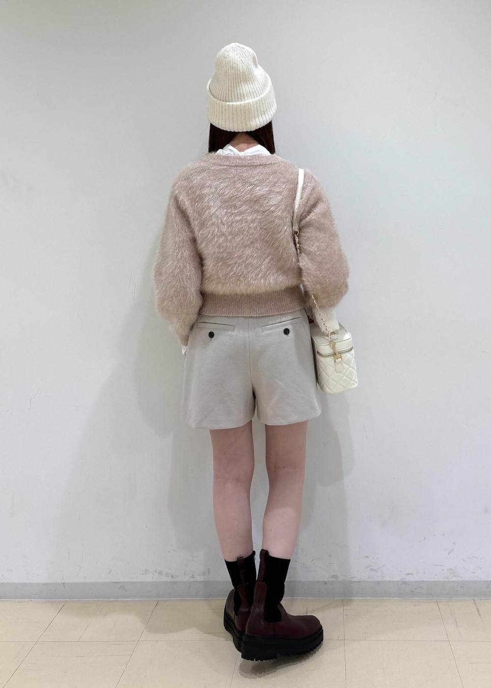 ブラウン系のブーツ、ベージュ系のその他パンツ、ホワイト系のハンドバッグを着用したレディースの冬コーディネートの3枚目の写真