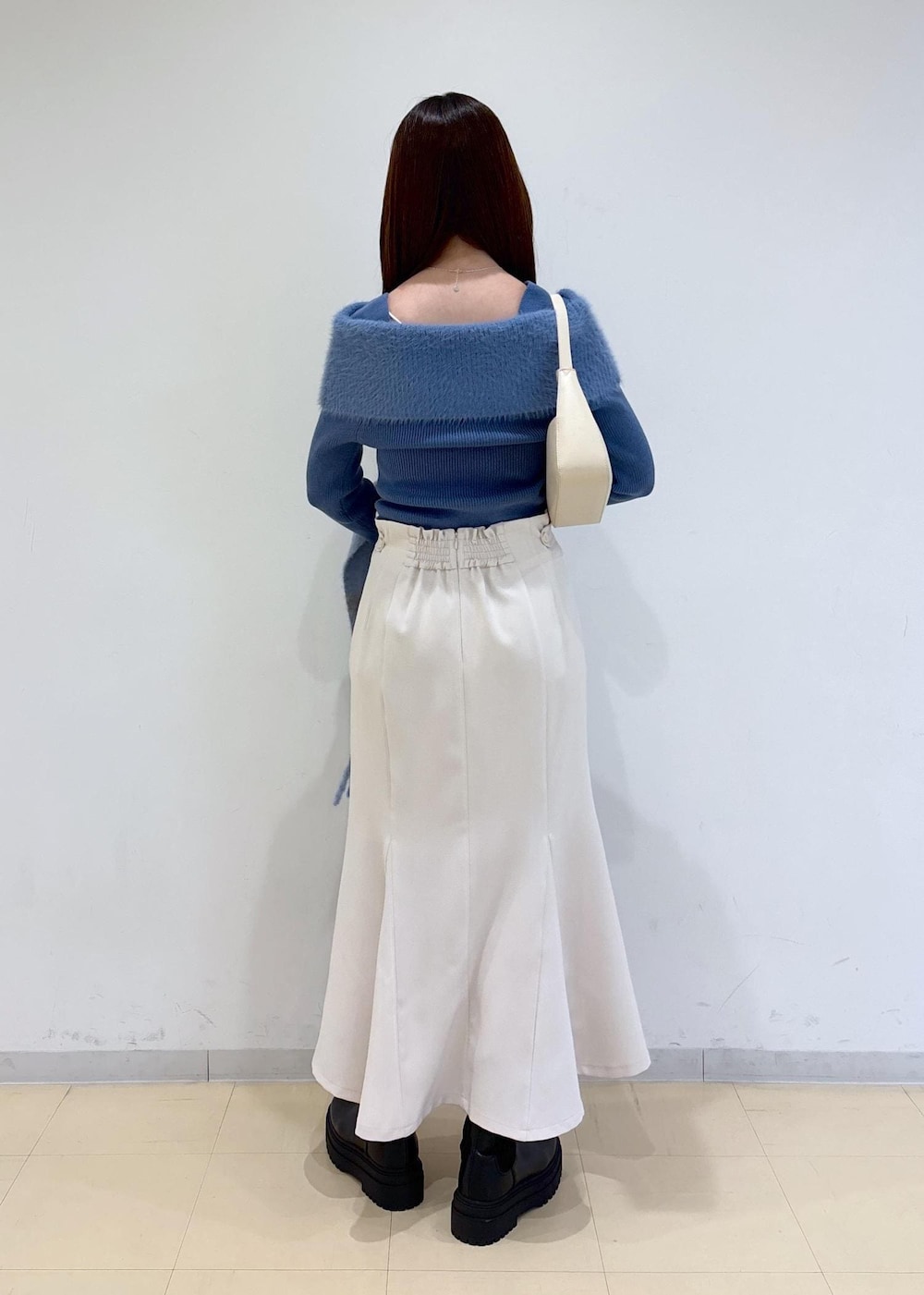 ホワイト系のショルダーバッグ、ブラック系のブーツ、ブルー系のニット/セーターを着用したレディースの秋コーディネートの4枚目の写真