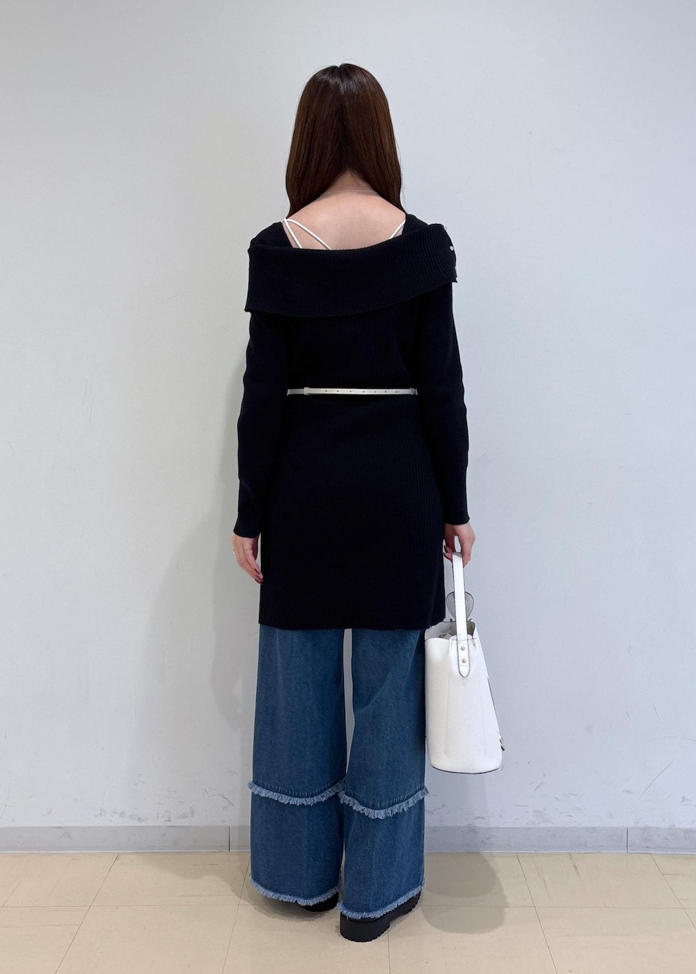 ブルー系のデニムパンツ、ブラック系のブーツ、ホワイト系のショルダーバッグを着用したレディースの秋コーディネートの4枚目の写真