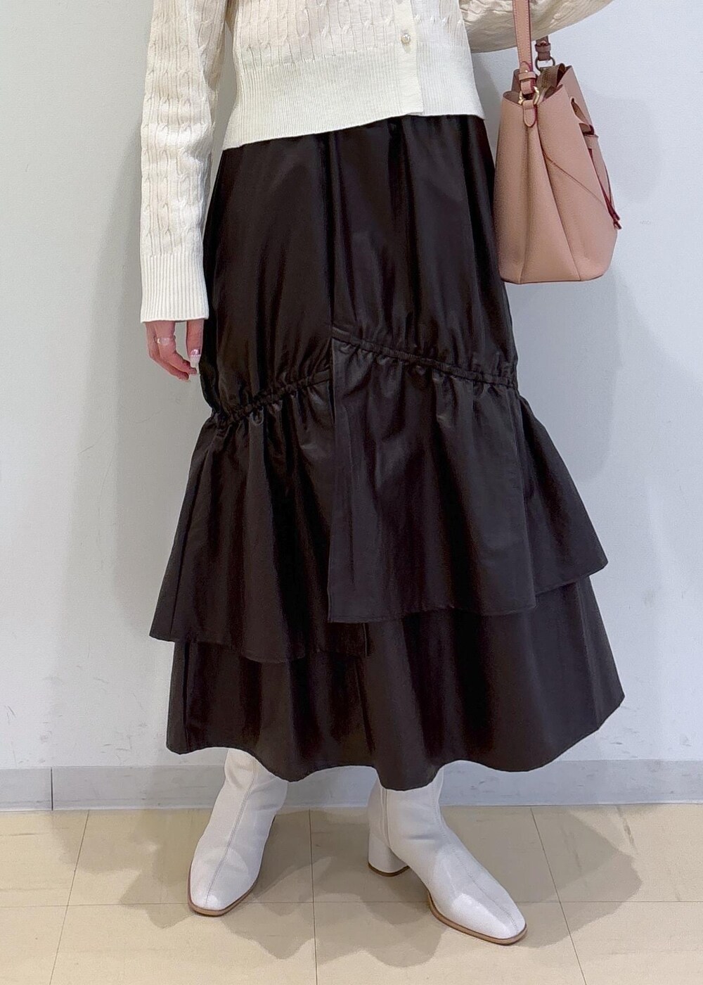 ピンク系のショルダーバッグ、ホワイト系のブーツ、ブラウン系のスカートを着用したレディースの冬コーディネートの5枚目の写真