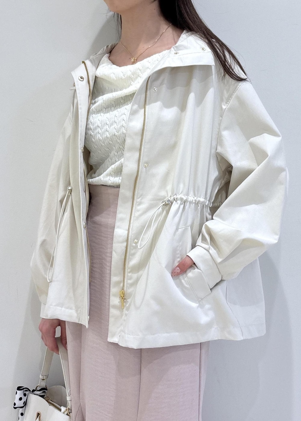 ホワイト系のショルダーバッグ、ブラック系のパンプス、ホワイト系のナイロンジャケットを着用したレディースの春コーディネートの5枚目の写真