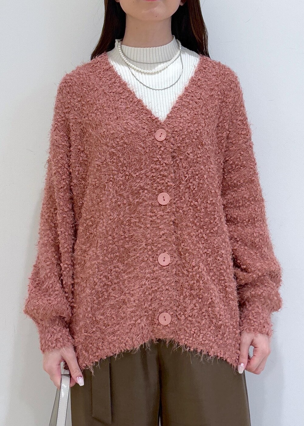 ブラウン系のブーツ、ピンク系のカーディガン/ボレロ、ホワイト系のニット/セーターを着用したレディースの冬コーディネートの6枚目の写真