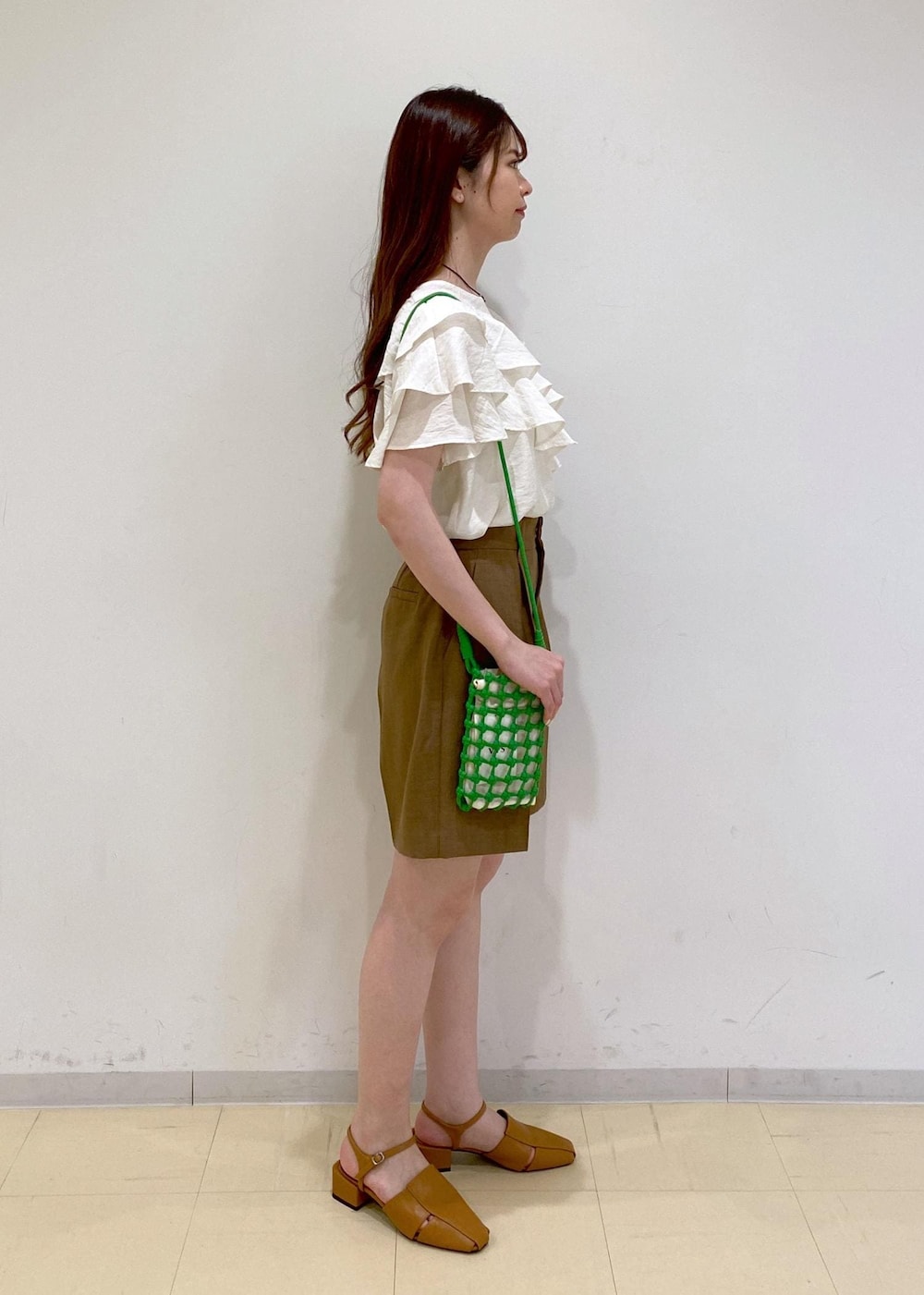 イエロー系のサンダル、ホワイト系のシャツ/ブラウス、グリーン系のショルダーバッグを着用したレディースの夏コーディネートの2枚目の写真